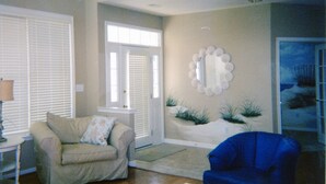 A living room with a beige sofa, a blue armchair, and a decorative wall piece. - Gorgeous Home in OC: Pools, Kayak, Fishing Pier, 5min to beach & Boardwalk, Golf (Berlin)