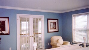 A bedroom with a white bed, a chair, two doors, and two windows. - Gorgeous Home in OC: Pools, Kayak, Fishing Pier, 5min to beach & Boardwalk, Golf (Berlin)
