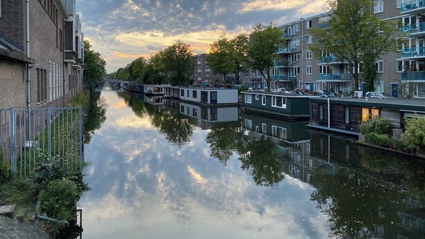 A canal with narrowboats, reflecting the sky and buildings.