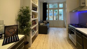 A modern kitchen with a built-in stove, wooden flooring, and a dining area with a sofa.