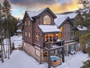 A large, multi-story lodge with a stone foundation, a hot tub, and a deck area. - Slopeside Saddlewood: True Ski-in/Out, Private Hot Tub, Grill, Shuttle (Breckenridge)