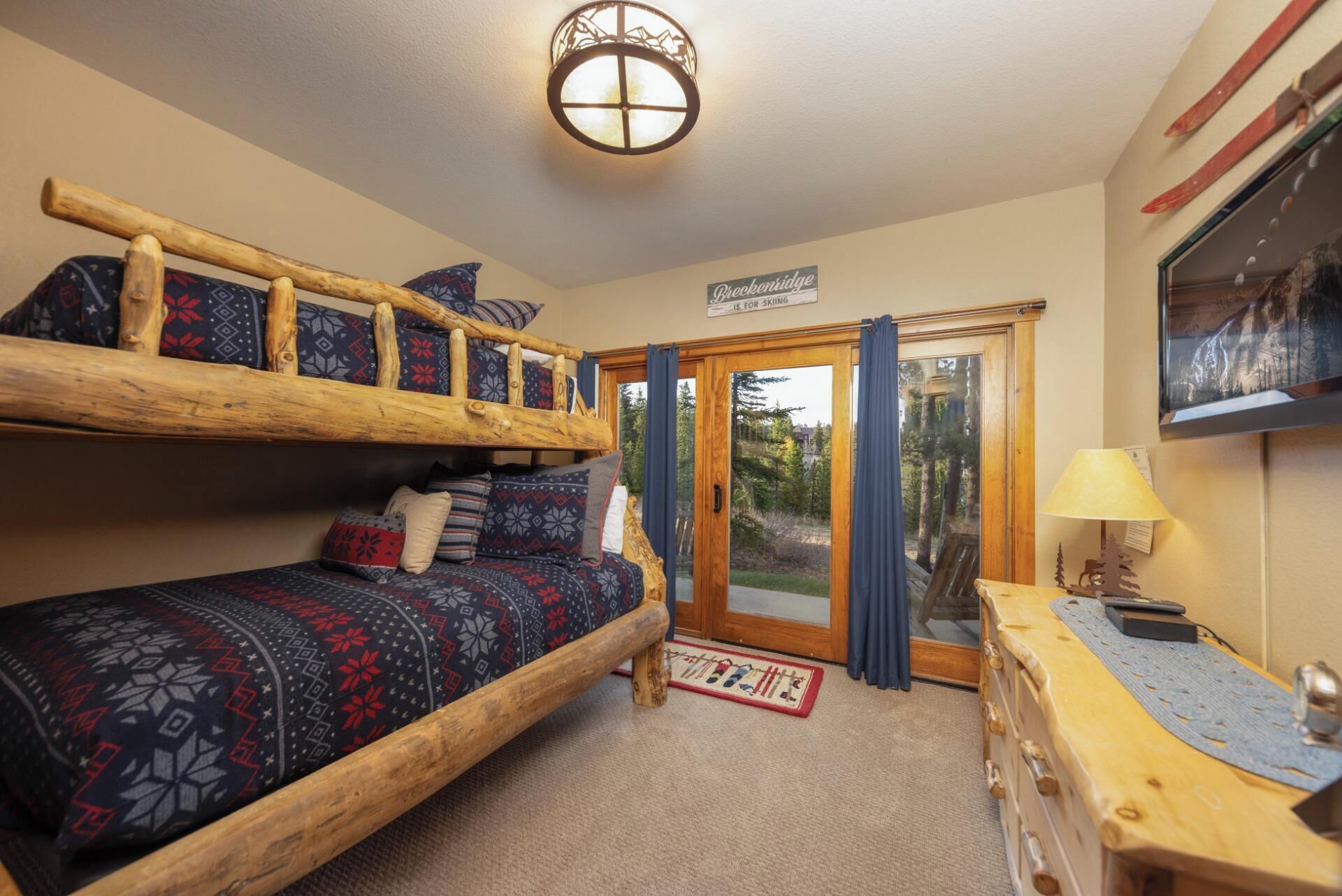 A cozy room with a bunk bed, a desk with a lamp, and a sign indicating skiing facilities.
