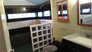 Een badkamer met een wit wastafelmeubel, een spiegel en een douchehoek.