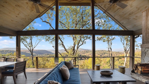 Une terrasse en bois avec un canapé bleu, une table et une cheminée.