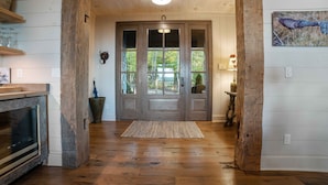 Un intérieur en bois avec une cheminée, une grande porte en bois et un tapis sur le sol.