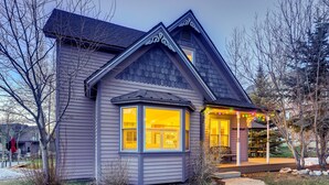 A house with a gabled roof, a bay window, and a porch with outdoor seating.