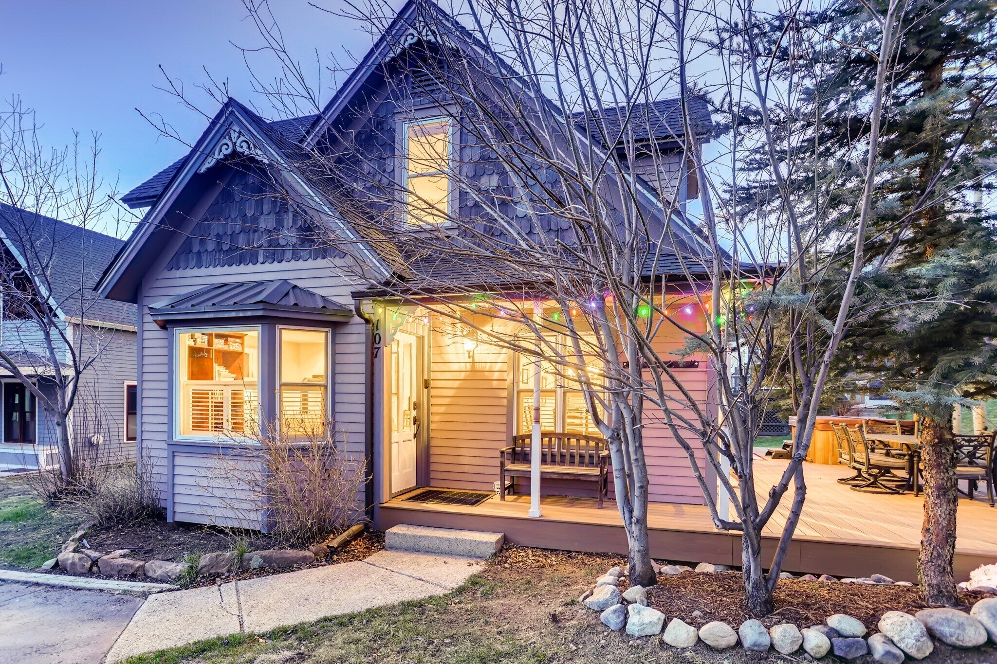 A two-story house with a porch, a small garden, and a deck.