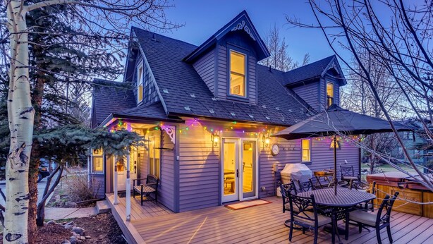 A two-story house with a deck, a covered outdoor seating area, and a visible garage.