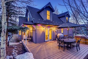 A two-story house with a deck, a covered outdoor seating area, and a visible garage. - Chalet Montagne: Charming Pet-Friendly Home, Private Hot Tub, Walk to Main St (Breckenridge)