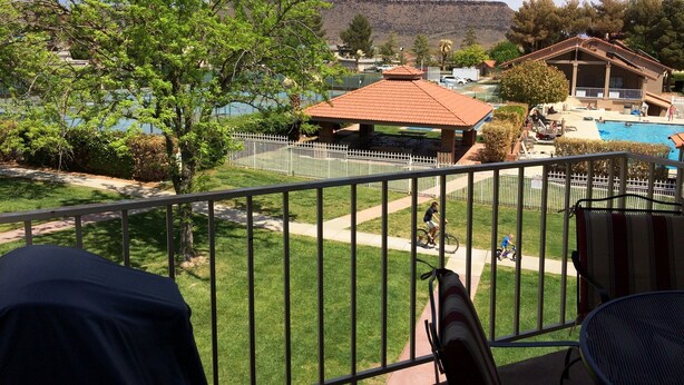 Un balcón con vistas a una piscina, un pabellón y una montaña al fondo.