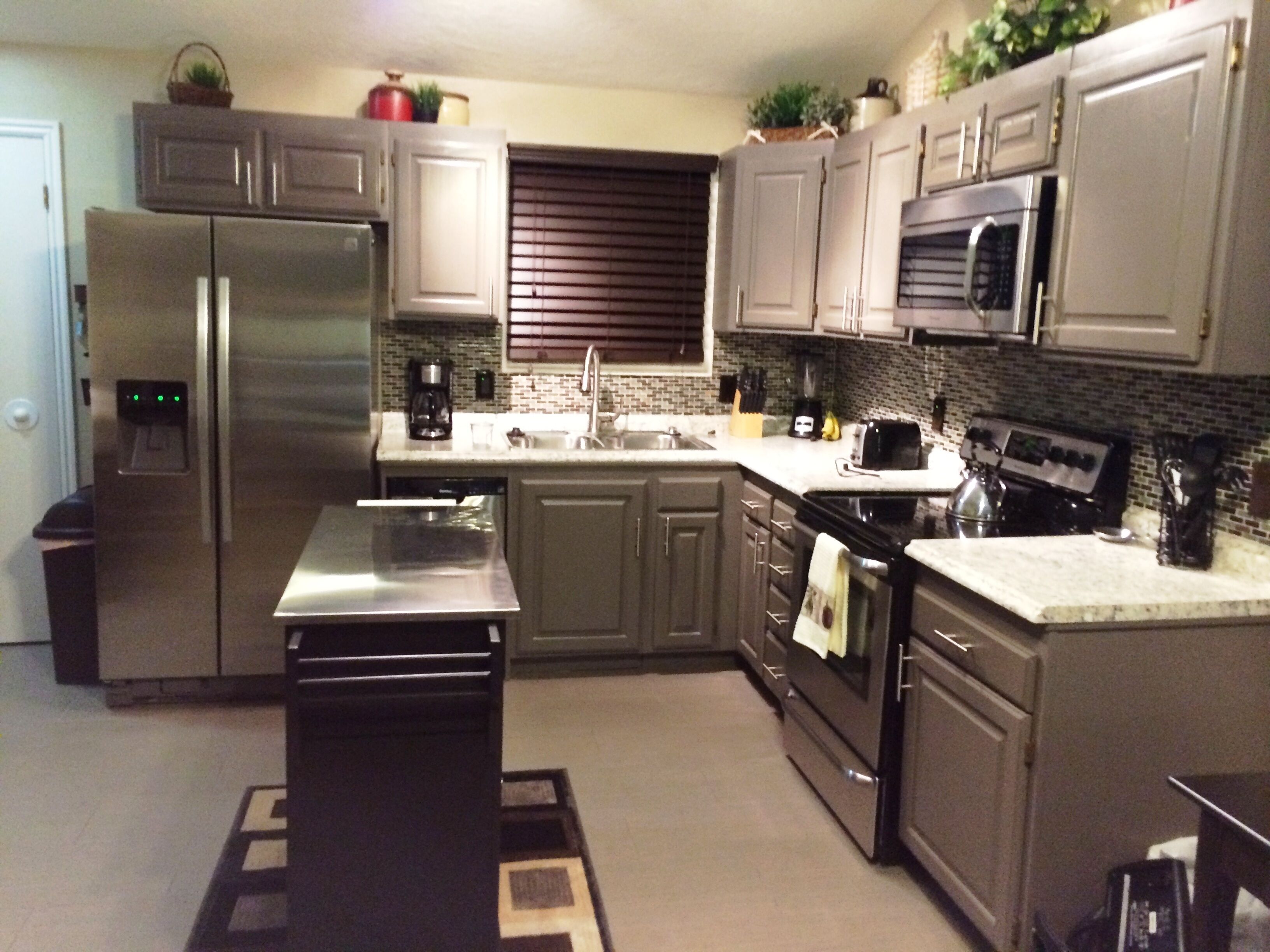 A modern kitchen with stainless steel appliances, dark wooden cabinets, and a tiled backsplash.