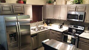 Una cocina moderna con electrodomésticos de acero inoxidable, un lavamanos doble y un microondas.