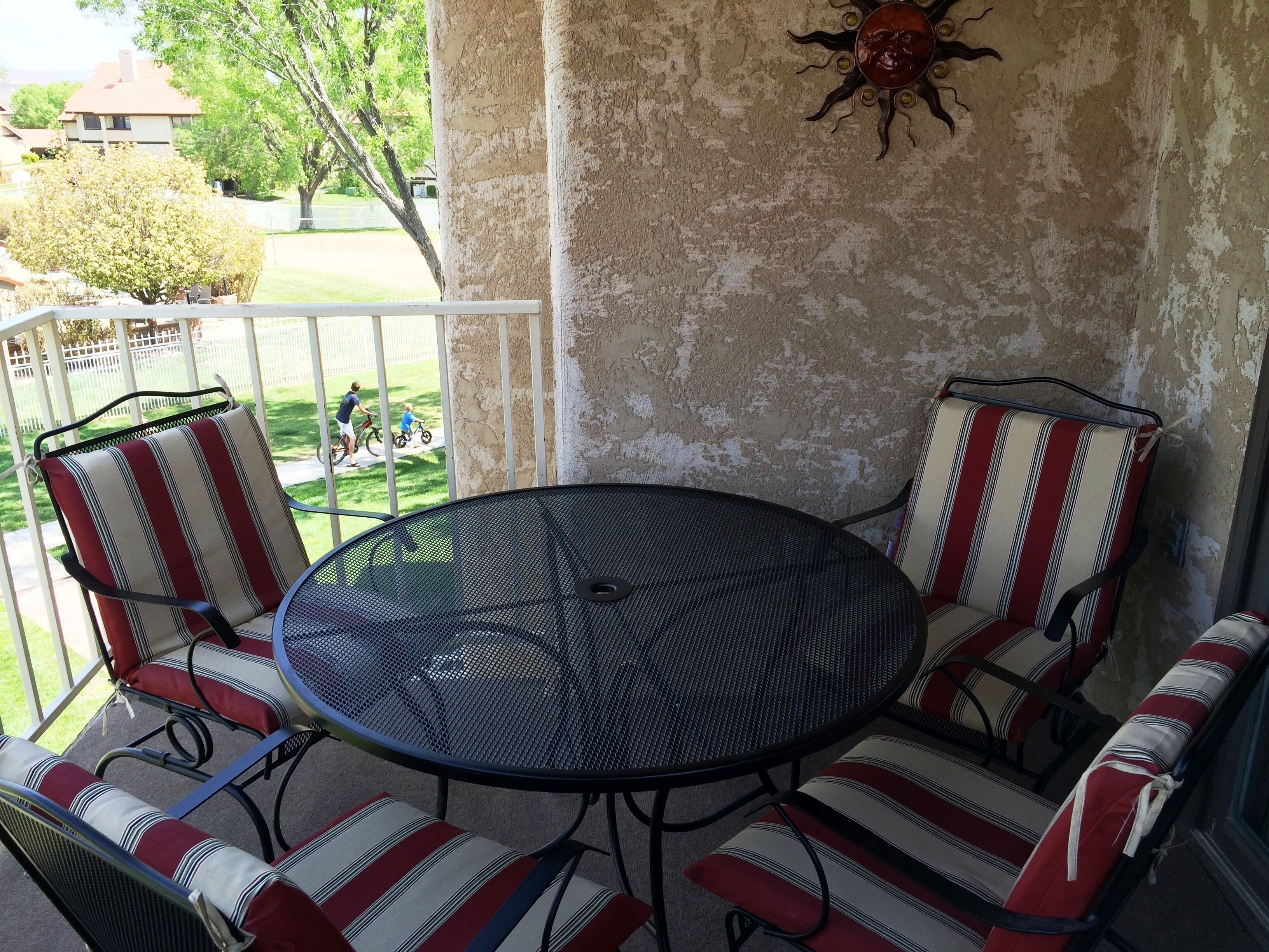 A balcony with a round table and two striped chairs.