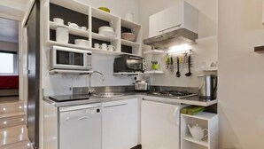 Uma cozinha moderna com armários brancos, micro-ondas embutido, torradeira e fogão.