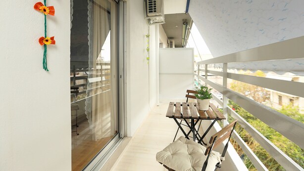 A balcony with a table, chairs, and a potted plant. - Cosy & Bright 2 Bedroom Apartment in Koukaki (Athens)