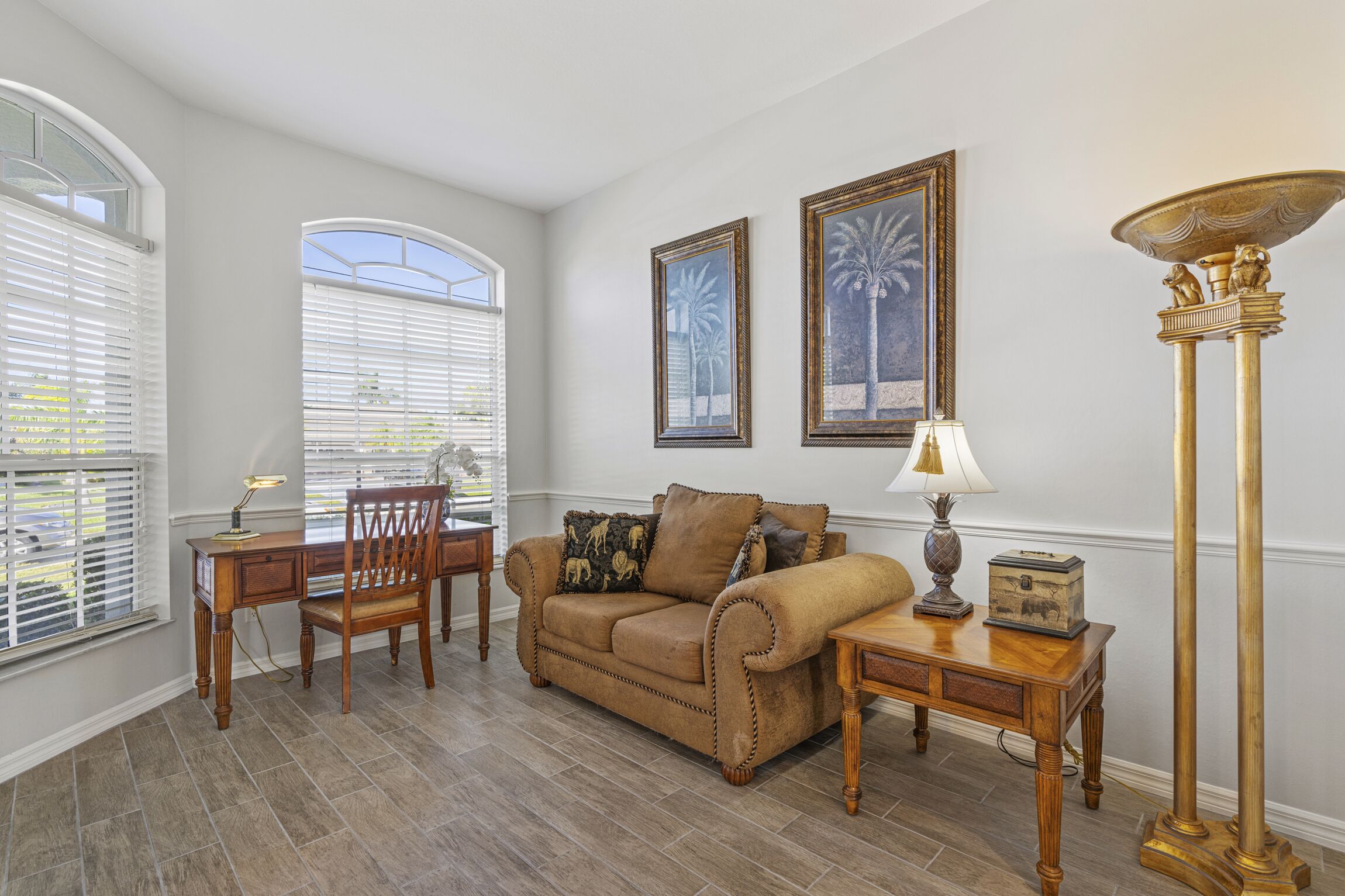 A living room with a brown sofa, a wooden coffee table, a lamp, and two framed pictures on the wall.