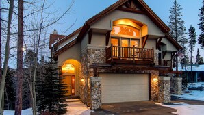 Une maison à deux étages avec une façade en pierre, un balcon doté de balustrades en bois et un garage.
