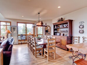 Un comedor amplio con mobiliario de madera, ventanas grandes y vistas al exterior.
