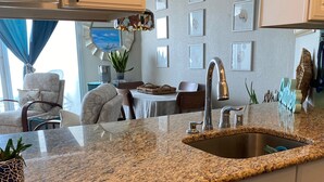 A kitchen with white cabinets, a granite countertop, a stainless steel sink, and decorative starfish.