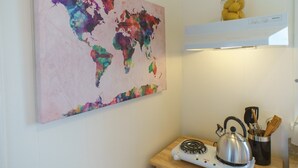 Une cuisine avec une carte du monde aux couleurs vives, une bouilloire et un bocal de citrons sur le plan de travail.