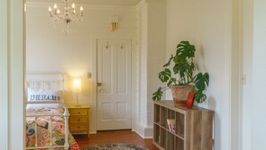 Une chambre à coucher avec un lit, une table de chevet, une commode et une plante en pot.