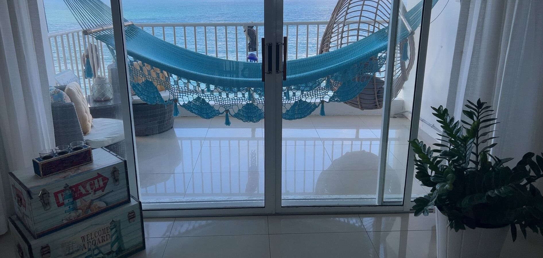 A balcony with a hammock, a view of the ocean, and a potted plant.