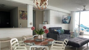 A modern living room with a glass dining table, white chairs, a grey sofa, and a large decorative globe light. - OCEAN VIEW GORGEOUS 1 BEDROOM CONDO APT A MILLION DOLLAR VIEW.5stars☀️BEST APT (Luquillo)