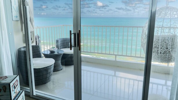 A balcony with a view of the ocean, wicker furniture, and a white decorative cage. - OCEAN VIEW GORGEOUS 1 BEDROOM CONDO APT A MILLION DOLLAR VIEW.5stars☀️BEST APT (Luquillo)