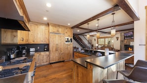A modern kitchen with wooden cabinets, a central island, and a fireplace. - Retreat at Lewis Ranch: Walk to Lift, Private Hot Tub, Shuttle, Gas Grill (Copper Mountain)
