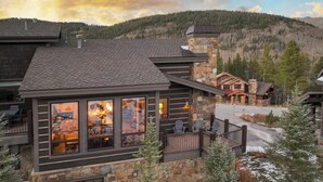 A lodge with a stone facade, large windows, and a deck with chairs. - Retreat at Lewis Ranch: Walk to Lift, Private Hot Tub, Shuttle, Gas Grill (Copper Mountain)