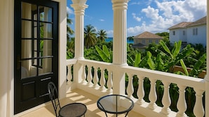A balcony with white balustrades, a black door, and a glass table. - Villa Serenity · 5BR Fully Staffed Oceanview Villa w/ Chef, Pool & Beach Access (Rio Nuevo bay)