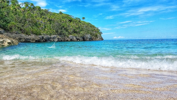 A beach with clear turquoise water, a rocky shoreline, and lush green vegetation on a hillside. - Villa Serenity · 5BR Fully Staffed Oceanview Villa w/ Chef, Pool & Beach Access (Rio Nuevo bay)