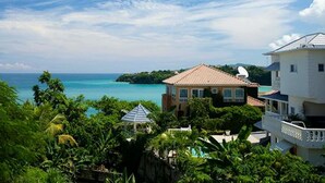 A coastal property with a view of the ocean, surrounded by lush greenery and a clear sky. - Villa Serenity · 5BR Fully Staffed Oceanview Villa w/ Chef, Pool & Beach Access (Rio Nuevo bay)