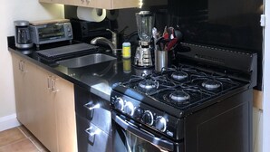 Una cocina con armarios de madera, una estufa negra, un tostador y una licuadora.