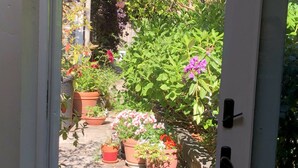 Un sendero en un jardín que lleva a una casa con macetas y flores.