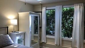 Un dormitorio con cama, mesita de noche, lámpara y un ventanal con cortinas.