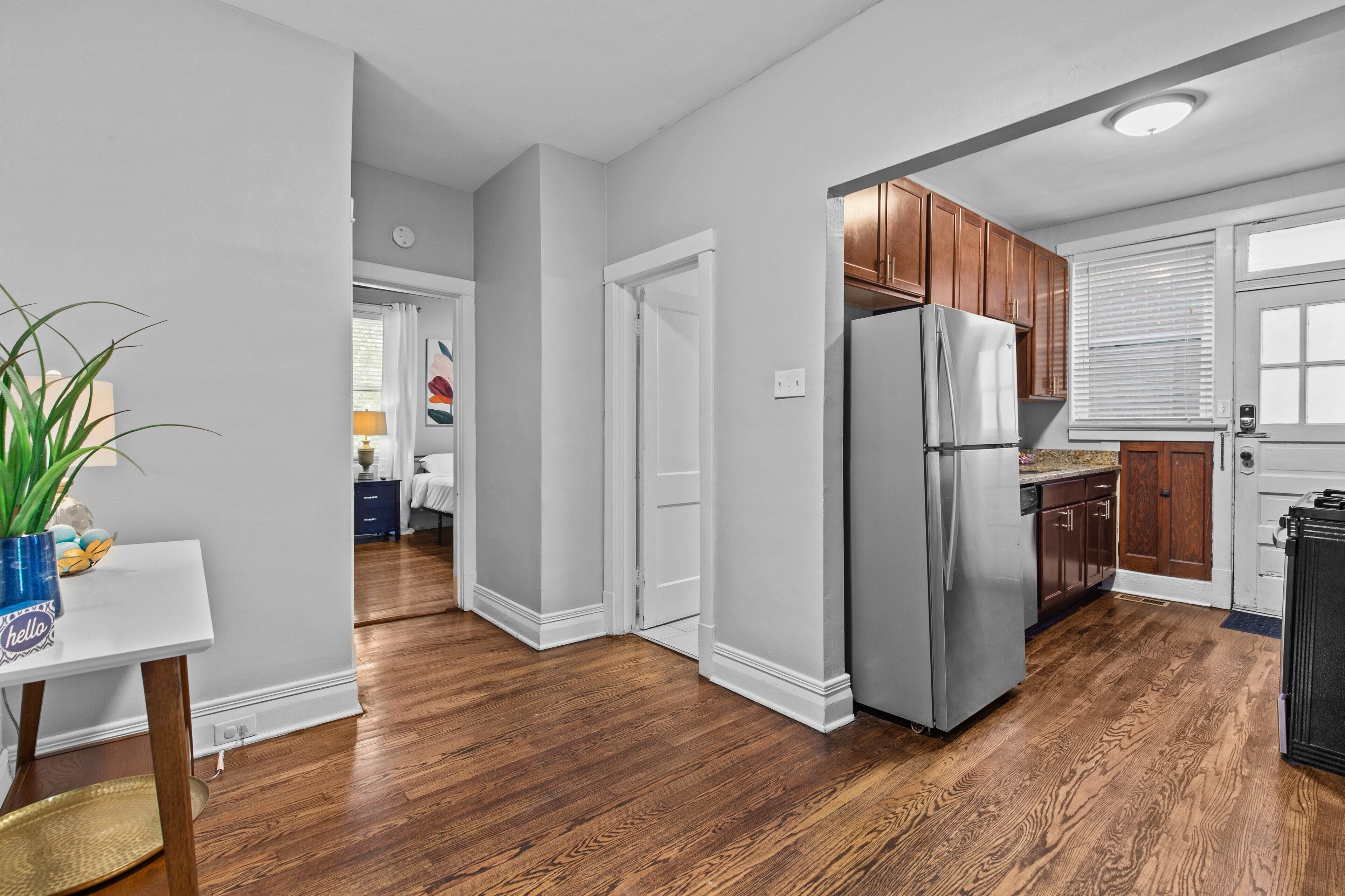 A modern kitchen with wooden cabinets, a stainless steel refrigerator, and a white countertop.