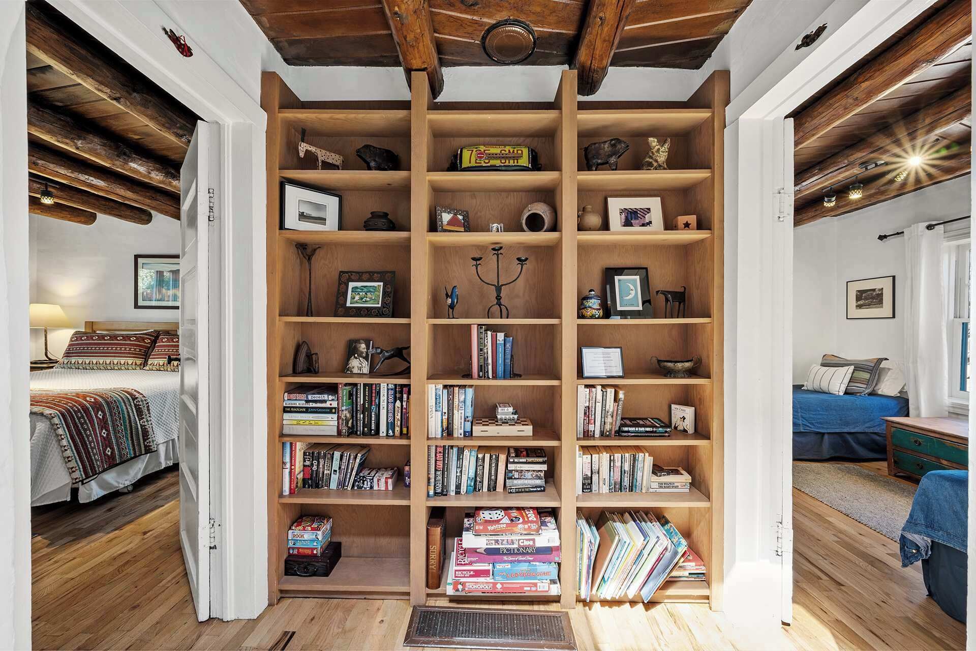 A cozy room with a wooden bookshelf filled with books and decorative items, a bed with patterned bedding, and a blue sofa.