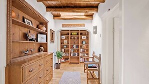 A hallway with wooden furniture, a bookshelf, and a potted plant. - Historic Adobe, Walk to Railyard and the Plaza (Santa Fe)