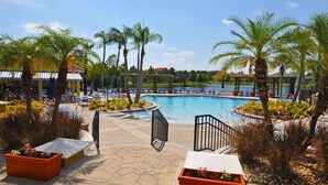 Un área de piscina con palmeras, sillas de descanso y cielo despejado.