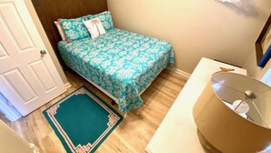 A small bedroom with a bed, a bedside table, a lamp, and a wall-mounted drying rack. - Cutest Cottage on the Beach- FREE WIFI and Laundry Included sleeps 5 (Carolina Beach)