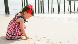 A child playing on the beach with wooden structures in the background. - Cutest Cottage on the Beach- FREE WIFI and Laundry Included sleeps 5 (Carolina Beach)