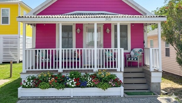 A pink house with a white porch and a number '303' on the front. - Cutest Cottage on the Beach- FREE WIFI and Laundry Included sleeps 5 (Carolina Beach)