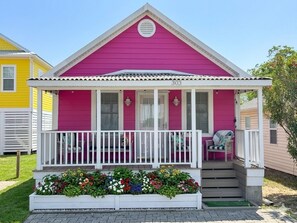 A pink house with a white porch and a number '303' on the front.