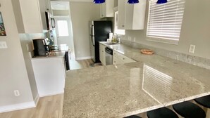 A modern kitchen with a large island, bar stools, and pendant lights. - Cutest Cottage on the Beach- FREE WIFI and Laundry Included sleeps 5 (Carolina Beach)