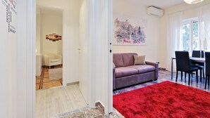 A modern living room with a red rug, a purple sofa, and a cityscape painting on the wall.