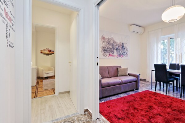 A modern living room with a red rug, a purple sofa, and a cityscape painting on the wall. - The Number 44 - Delightful house in the Vatican area. PRIVATE TERRACE. (Roma)
