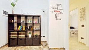 A modern hotel lobby with a marble floor, a dark wooden bookshelf, and a welcome wall with multilingual greetings.
