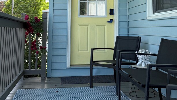 A porch with a yellow door, a window, and a table with chairs. - Lakeview Bungalow with easy walk to Village Fun, Eats, Wine, Craft Beer & Marina (Watkins Glen)