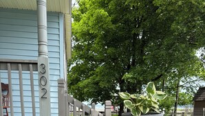 A house with a number '302' on the door, a wooden fence, a large planter with a plant, and a stone pathway. - Lakeview Bungalow with easy walk to Village Fun, Eats, Wine, Craft Beer & Marina (Watkins Glen)